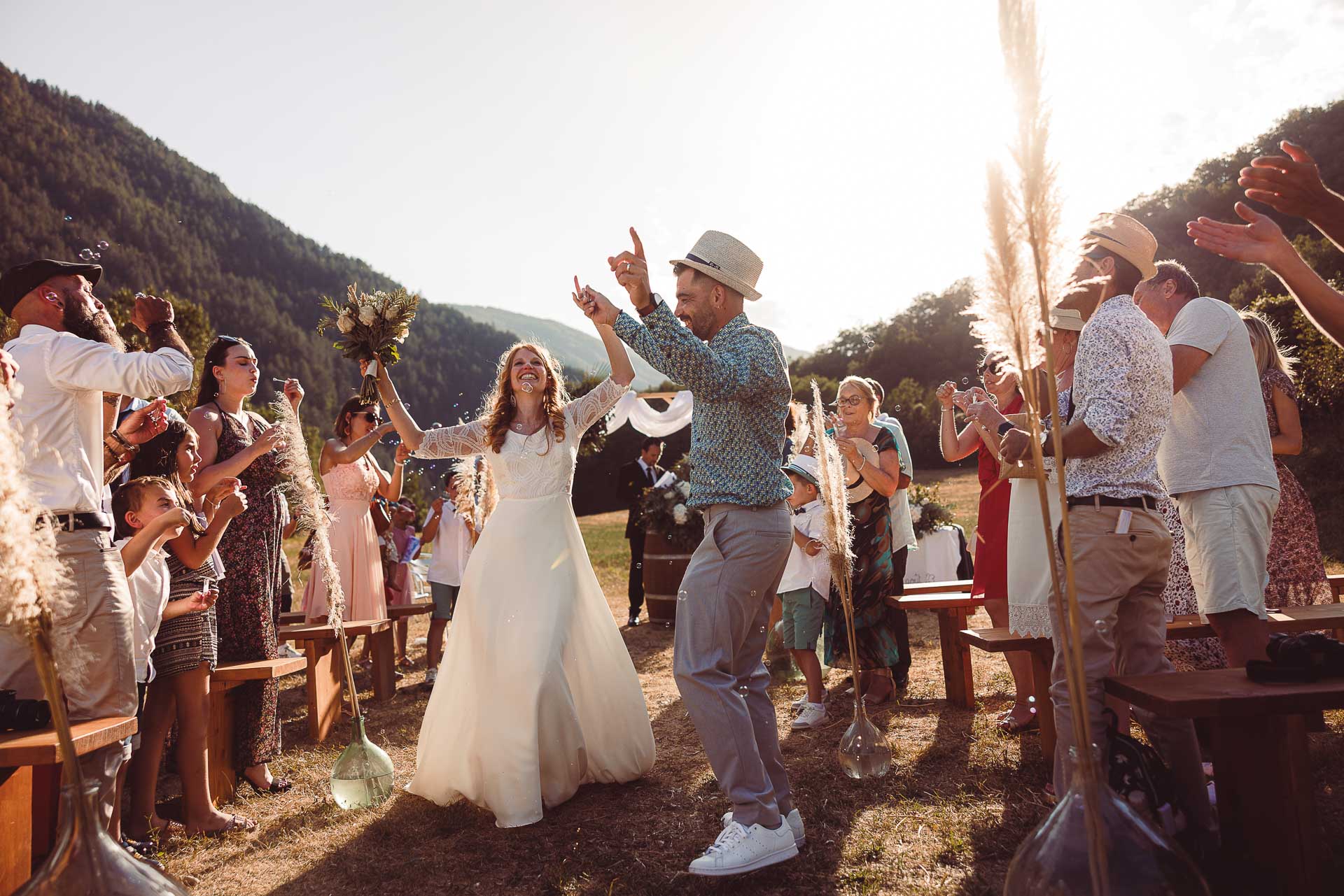 Newlyweds celebrating their outdoor ceremony exit with bubbles in the Provence mountains