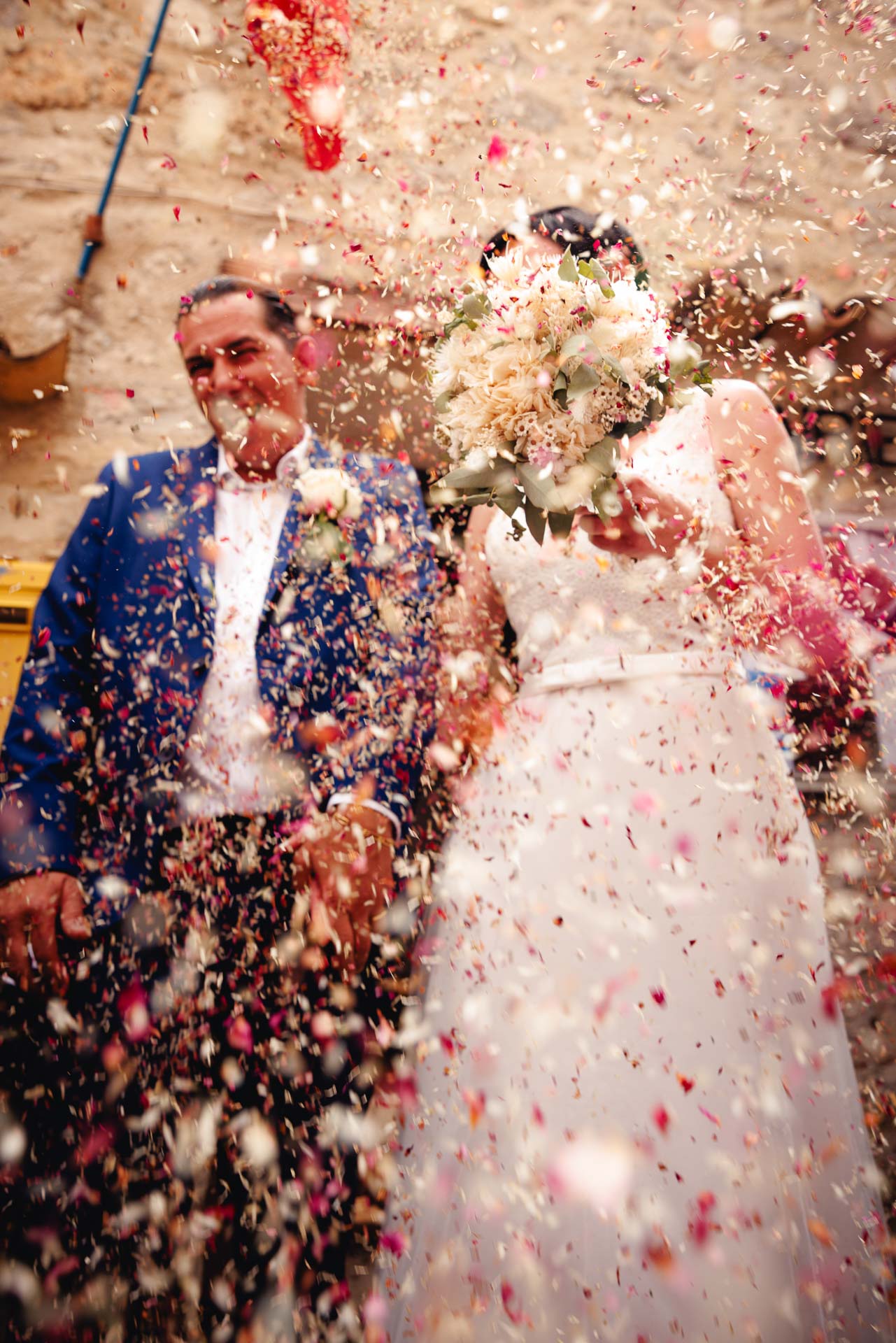 Couple kissing surrounded by guests in a stone village square