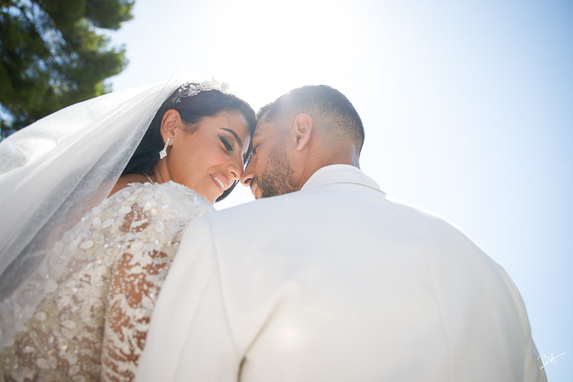 Bride and groom forehead to forehead under the Mediterranean sun